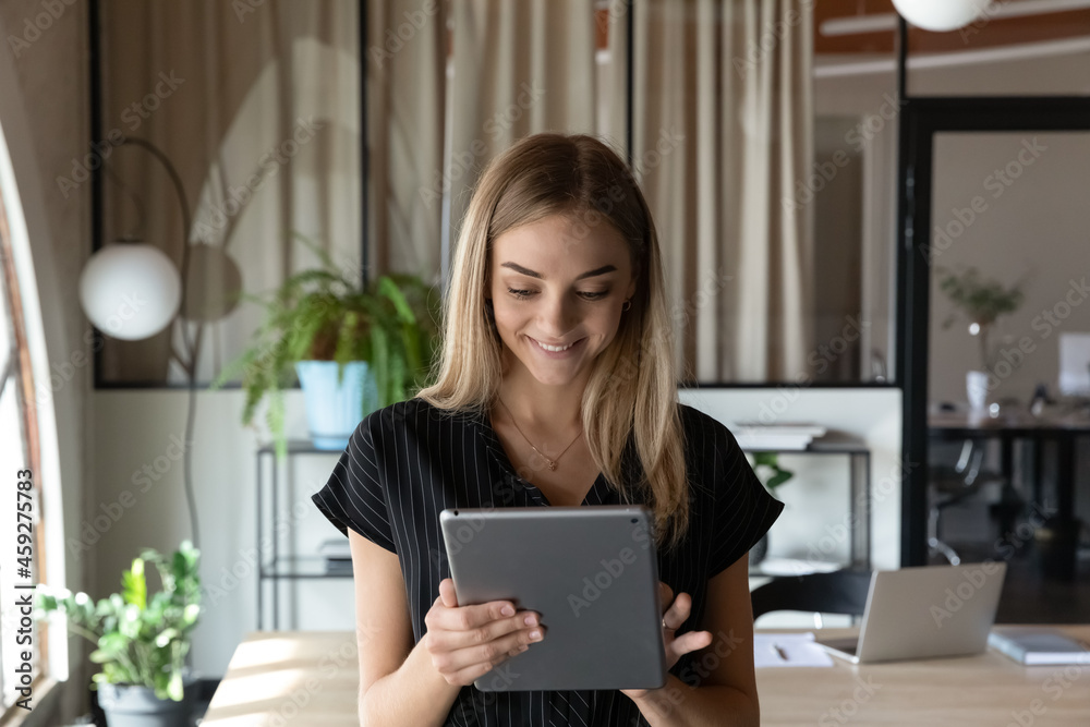 Happy young business woman using online app on tablet in office. Student using virtual learning service on pad computer. Professional making payments, giving consultation to client, chatting, working