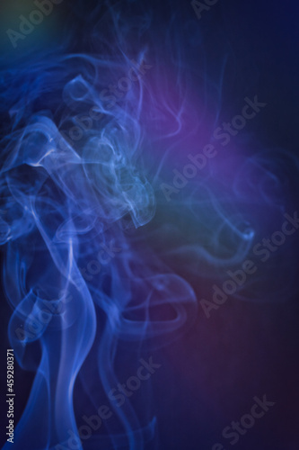 A vertical shot of smoke in colorfull backlight with a blue note