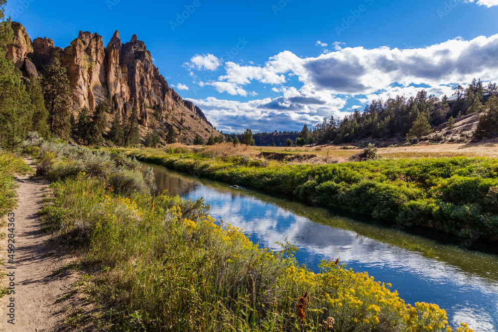 The river is flowing among the rocks. Colorful Canyon. Reflection of the yellow rocks in the river. Amazing landscape of yellow sharp cliffs. Smith Rock state park, Oregon