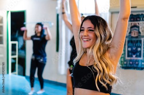 Smiling young latin hispanic woman exercising with crop top in an indoor space.