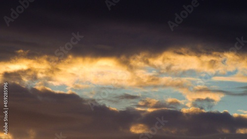 Teintes mordorées sous la base de nuages de moyenne altitude, pendant le coucher du soleil