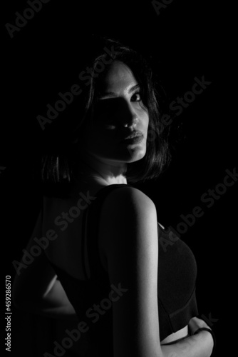 Portrait of attractive a young woman with cinematic lighting. Woman wearing a suspender bodysuit. Half naked sexy woman. Vertical shot. Dramatic monochrome  black and white photo.