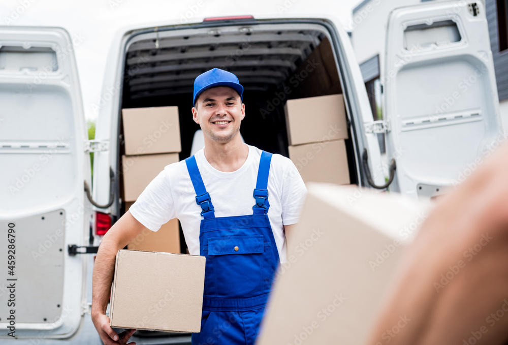 Two removal company workers unloading boxes from minibus into customer's home
