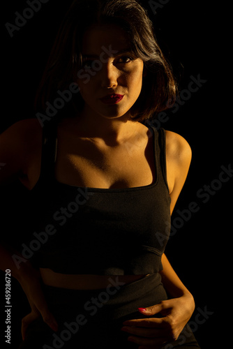 Portrait of attractive a young woman with cinematic lighting. Woman wearing a suspender bodysuit. Half naked sexy woman. Vertical shot.