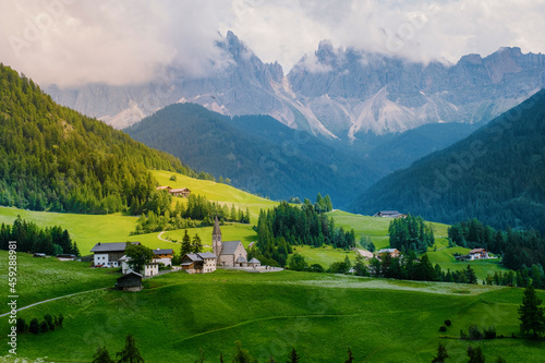 Santa Magdalena village in Val di Funes on the italian Dolomites. Autumnal view of the valley with colorful trees and Odle mountain group on the background. Italy Europe photo