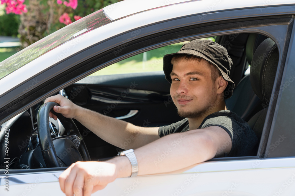 a young teen guy driving a new car. he has successfully passed the driver's license exam and is going on a road trip