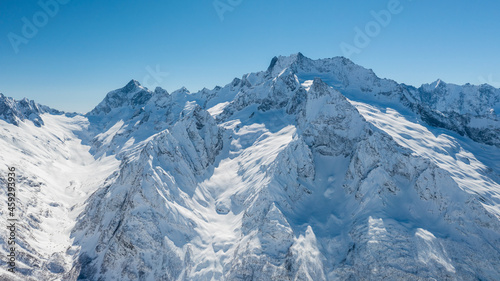 Caucasus Mountains, Panoramic view of the ski slope with the mountains Belalakaya, Sofrudzhu and Sulakhat on the horizon in winter day. Dombai ski resort, Western Caucasus, Karachai-Cherkess, Russia.
