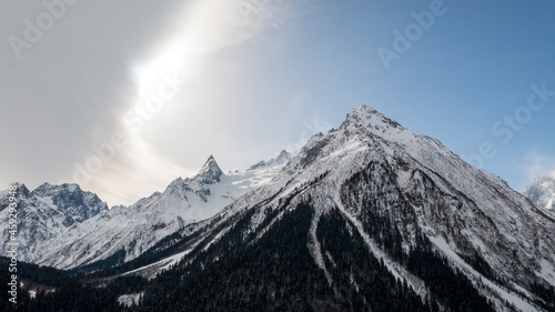 Caucasus Mountains, Panoramic view of the ski slope with the mountains Belalakaya, Sofrudzhu and Sulakhat on the horizon in winter day. Dombai ski resort, Western Caucasus, Karachai-Cherkess, Russia. photo