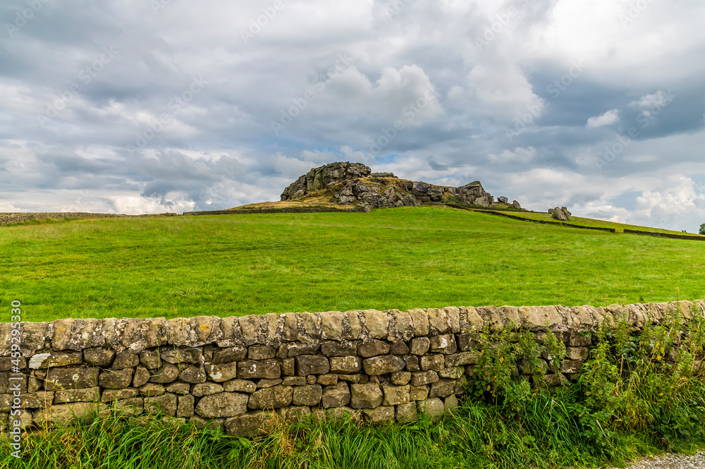 A view past a dry stone wall towards the Almscliffe crag in Yorkshire, UK in summertime