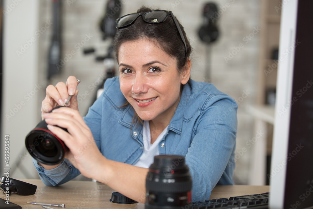 positive woman cleaning a camera lens with brush