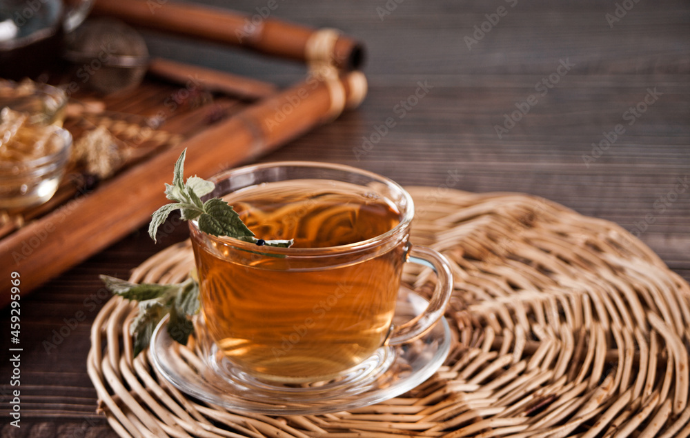Fototapeta premium Cup of herbal mint tea with dry herbs on the tray.