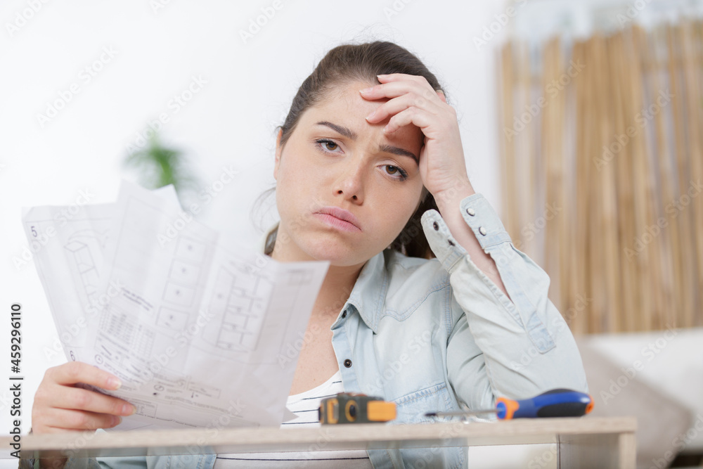 frustrated woman with self assembly furniture in kitchen frustrated woman with self assembly furniture in kitchen