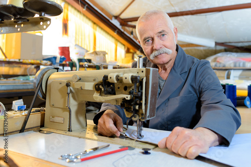 senior mechanic repairing industrial sewing machine in factory