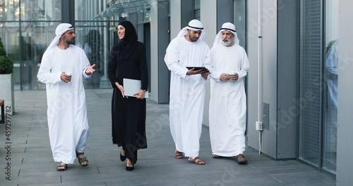 Fototapeta Walking arab people wearing kandura on business location