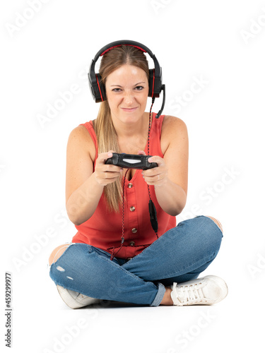 Young woman playing videogames with a controler and a headphones in a white background photo