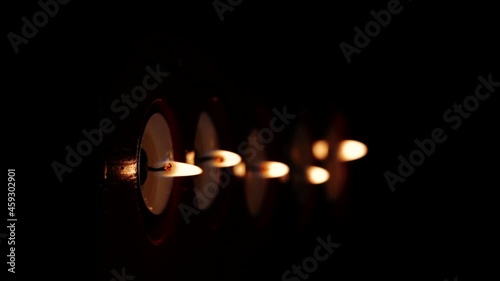 Close-up macro vertical footage of candle flames burning in the darkness.
