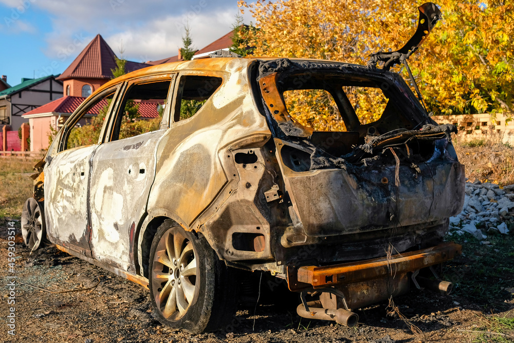 Fototapeta premium Burned-out car stands on the street in autumn