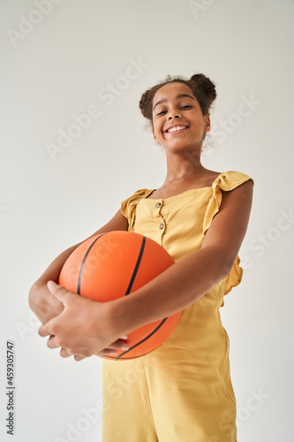 Black brunette little girl holding basketball ball