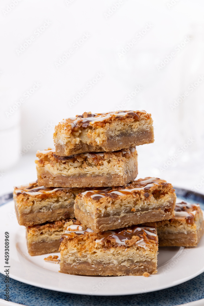 Coconut macaroon cookie bars squares stacked in a kitchen