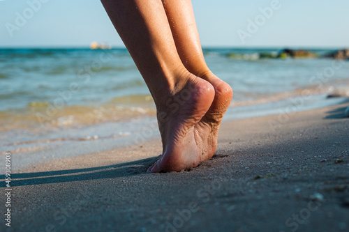 Female feet stand on tiptoes on a sandy beach on a summer day