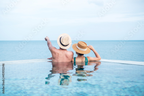 Happy couple in infinity pool at luxury hotel against ocean front., enjoy in tropical resort. Relaxing, summer,  travel, holiday, vacation , romance and weekend concept photo