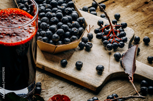 Fresh aronia berries and berry juice in a glass.