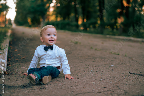 Portrait of a baby boy in a business suit on a walk in the park. Baby's first steps. Little gentleman.