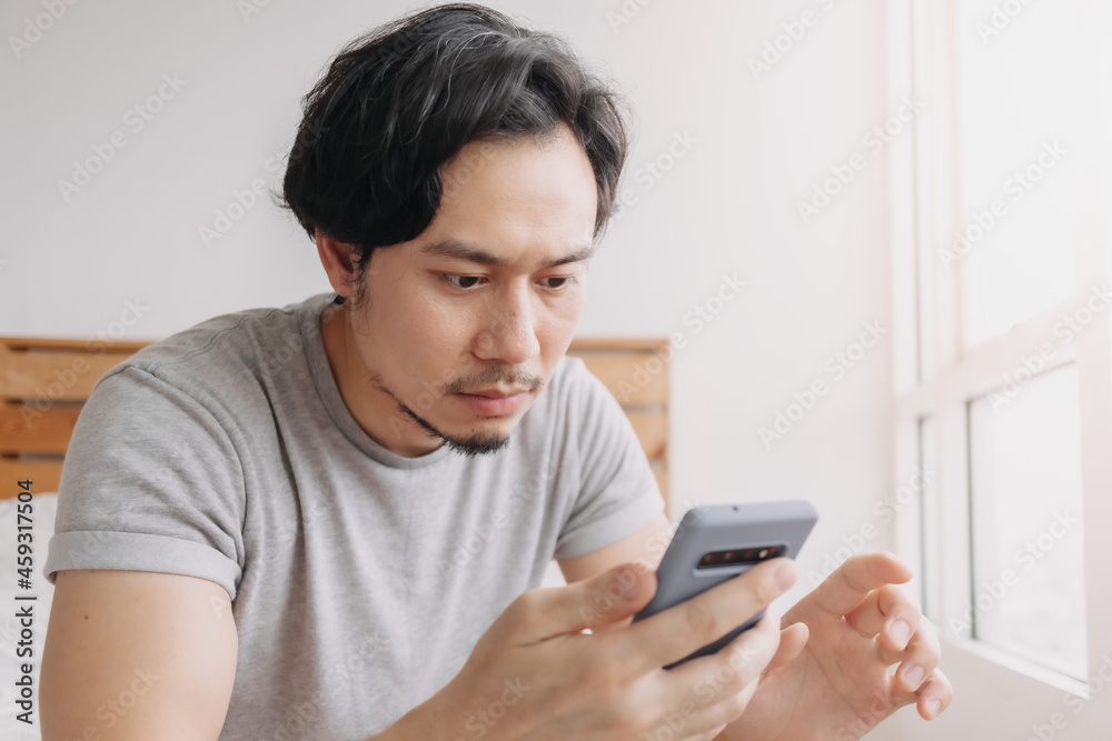 Asian man looking at smartphone with serious face. Asian man looking at smartphone with serious face.