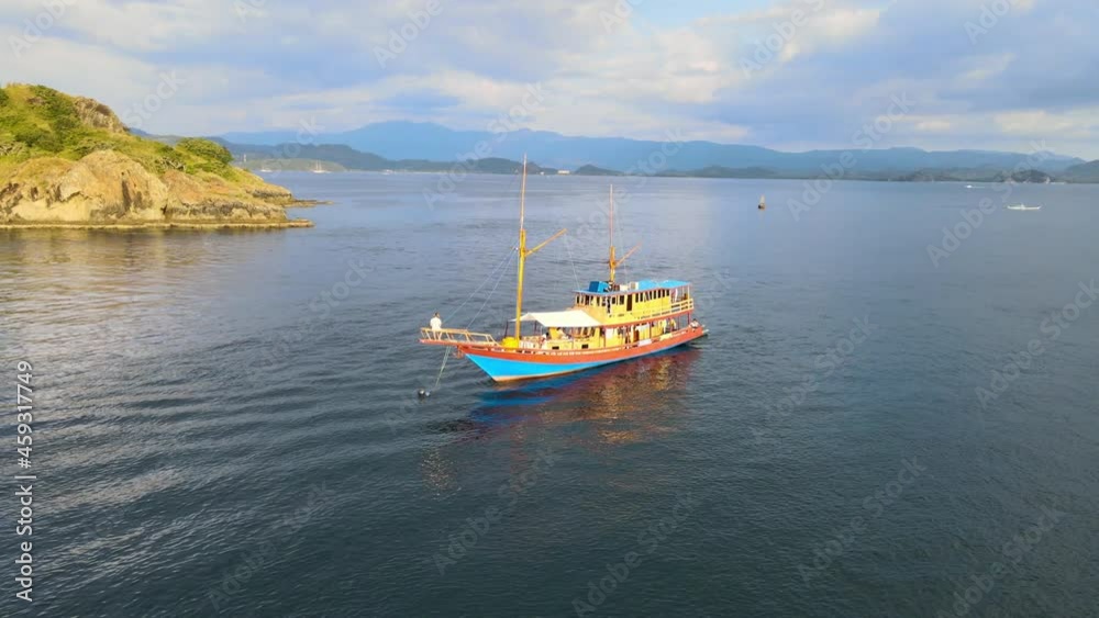 Flying around a boat sailing in a bay near the Komodo island in Indonesia. Drone view. Flying around a boat sailing in a bay near the Komodo island in Indonesia. Drone view.