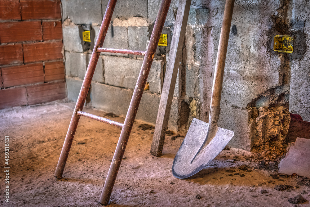 Shovel and ladder leaning on a rustic wall Shovel and ladder leaning on a rustic wall