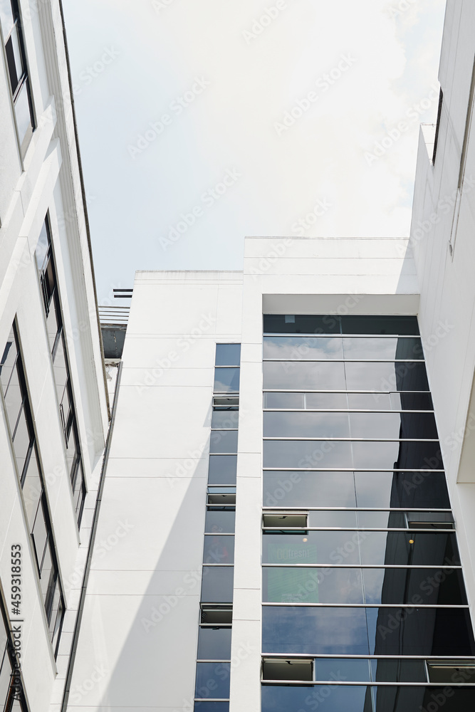 Obraz premium Large white building with huge dark and blue sales windows looking up clear blue clear sky