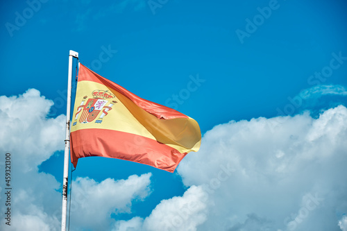 Spanish flag over blue sky with clouds