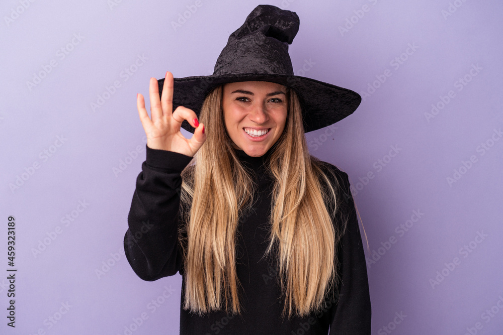 Young Russian woman disguised as a witch celebrating Halloween isolated on purple background cheerful and confident showing ok gesture. Young Russian woman disguised as a witch celebrating Halloween isolated on purple background cheerful and confident showing ok gesture.