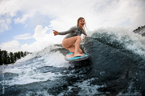 cheerful woman rides down the wave sitting on a wakeboard. Summertime leisure