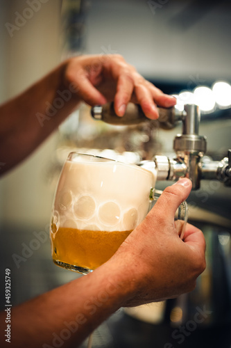 Experienced bartender pouring draft beer into a glass. Pilsner  also pilsener or simply pils  in a glass .