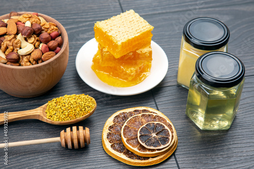 assortment of nuts and assorted dried citrus fruits and fresh floral honeycomb honey and pollen on kitchen wooden board. useful vitamin food for the human body