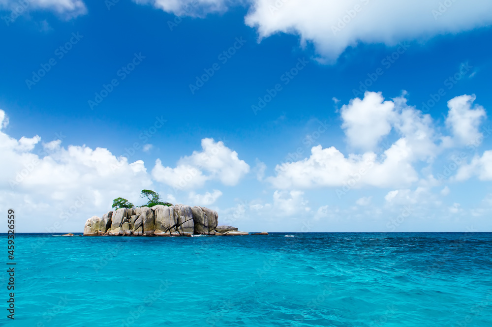 Deserted rocky island in the ocean. Covered with sparse vegetation and trees. The Seychelles. Deserted rocky island in the ocean. Covered with sparse vegetation and trees. The Seychelles.