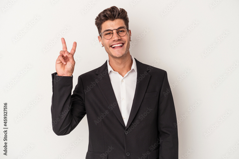 Young business caucasian man wearing headphones isolated on white background joyful and carefree showing a peace symbol with fingers. Young business caucasian man wearing headphones isolated on white background joyful and carefree showing a peace symbol with fingers.