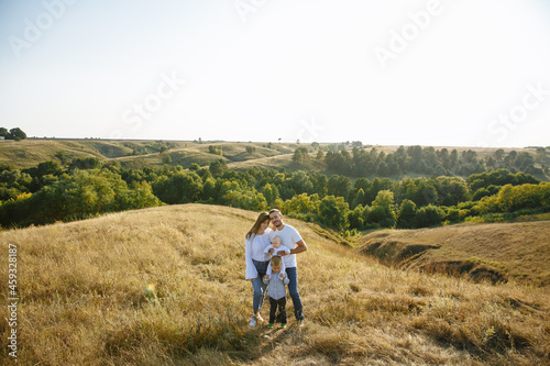 mom dad and two sons posing on the background of nature in a field with tall grass