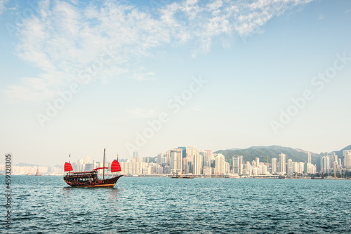 Traditional Chinese Junkboat sailing. Views of the skyscrapers background.