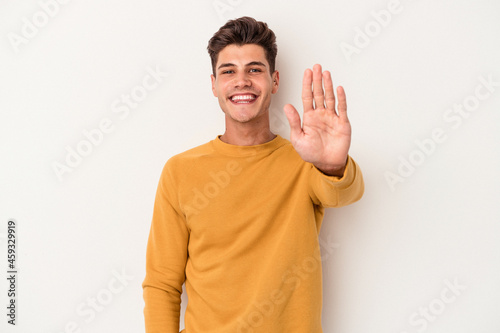 Young caucasian man isolated on white background smiling cheerful showing number five with fingers.