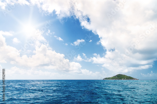 Deserted rocky island in the ocean. Covered with sparse vegetation and trees. The Seychelles.