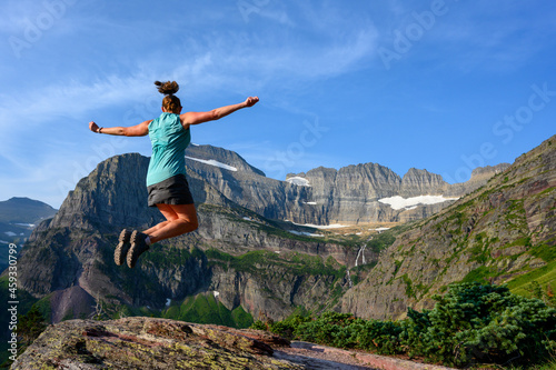 Woman Leaps With Arms Out At Grinnell Glacier