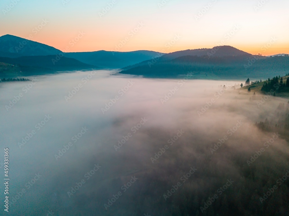 Fog spreads over the mountains at dawn. The sun rises on the horizon. Ukrainian Carpathians in the morning. Aerial drone view. Fog spreads over the mountains at dawn. The sun rises on the horizon. Ukrainian Carpathians in the morning. Aerial drone view.