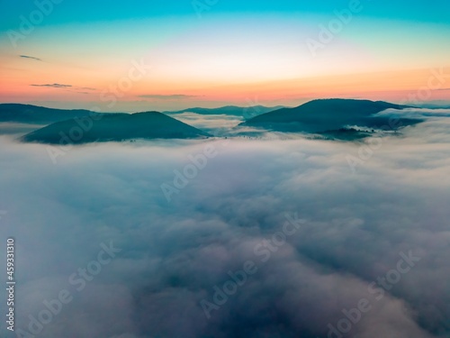 Fog in the mountain valley at dawn. Ukrainian Carpathians in the morning in the haze. Aerial drone view.