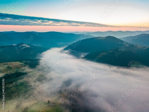 Fototapeta Naklejka Na Ścianę i Meble -  Fog in the mountain valley at dawn. Ukrainian Carpathians in the morning in the haze. Aerial drone view.