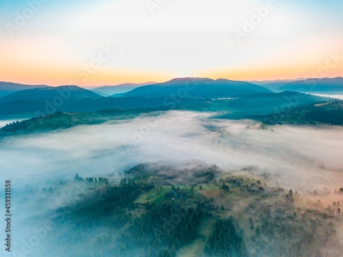Fototapeta Naklejka Na Ścianę i Meble -  Fog spreads over the mountains at dawn. The sun rises on the horizon. Ukrainian Carpathians in the morning. Aerial drone view.