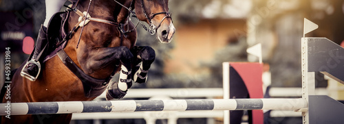 The shod hooves of a horse over an obstacle. The horse overcomes an obstacle. Equestrian sport, jumping. Overcome obstacles.