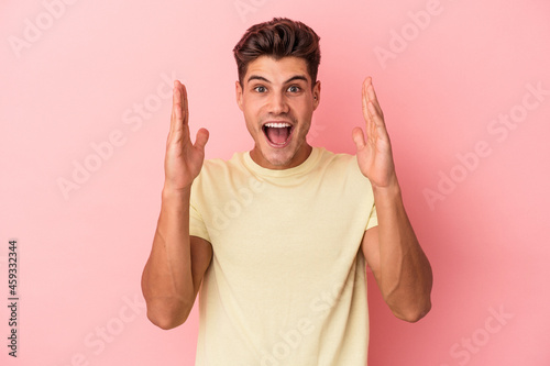 Young caucasian man isolated on pink background celebrating a victory or success, he is surprised and shocked.