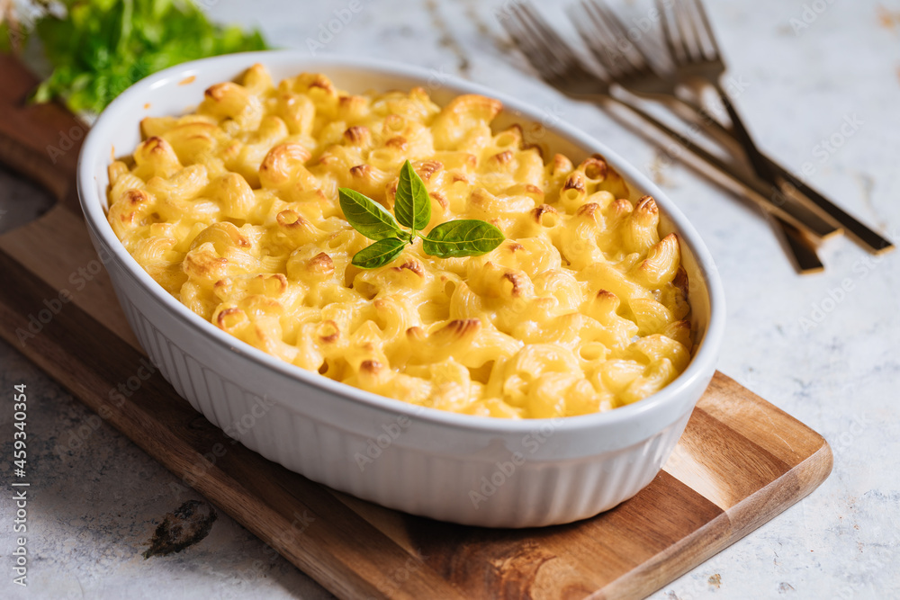 Mac and cheese with basil on top on a rustic wooden board Mac and cheese with basil on top on a rustic wooden board